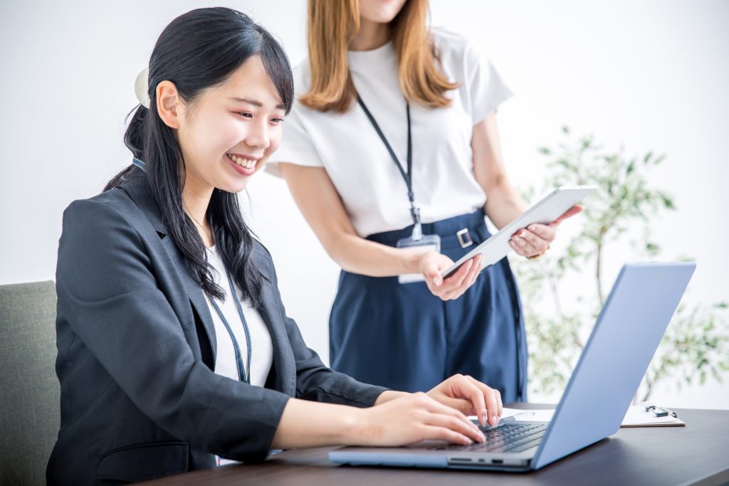 ノートPCの前で連携する女性ビジネスパーソン